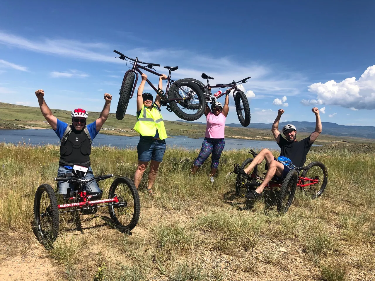 A group of people standing next to each other holding bikes.