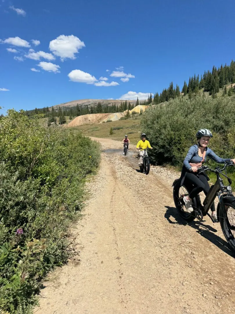 A group of people riding bikes on top of a dirt road.