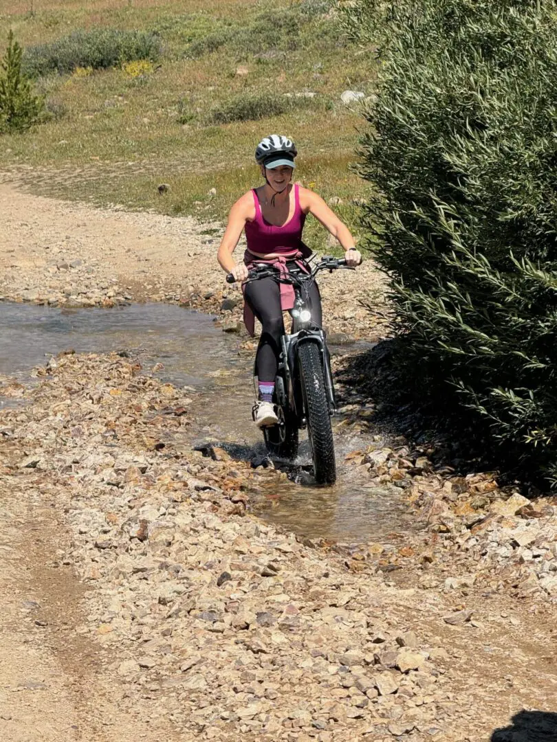 A woman riding a bike through some water