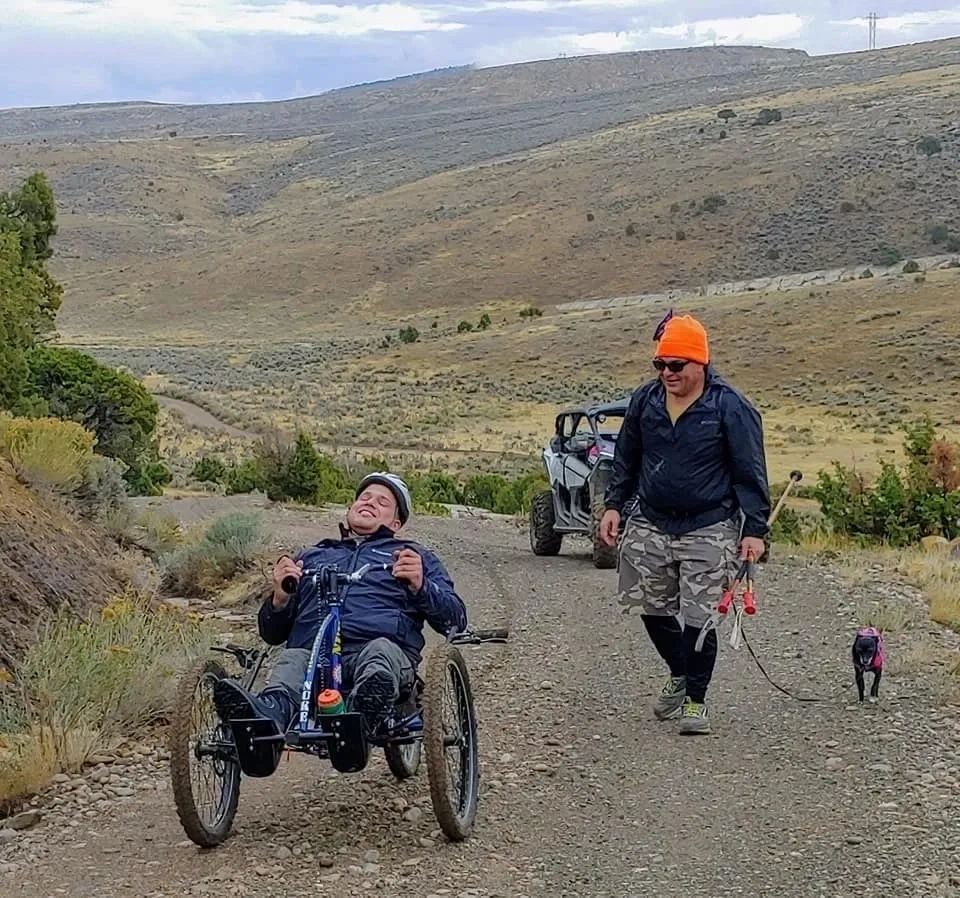 A man in a wheelchair is walking down the road