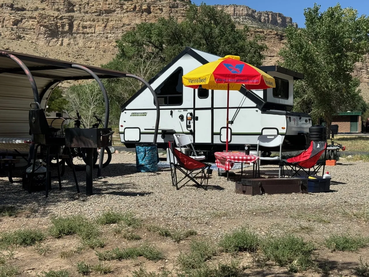 A white camper with an umbrella and some chairs