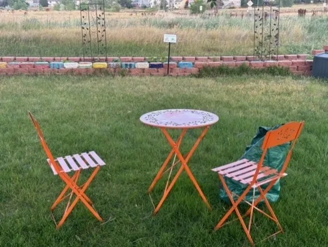 A table and two chairs in the grass.