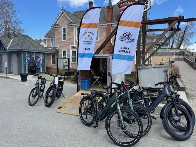 thumbnail_IMG_5577 E-bikes parked outside rental shop with banners.