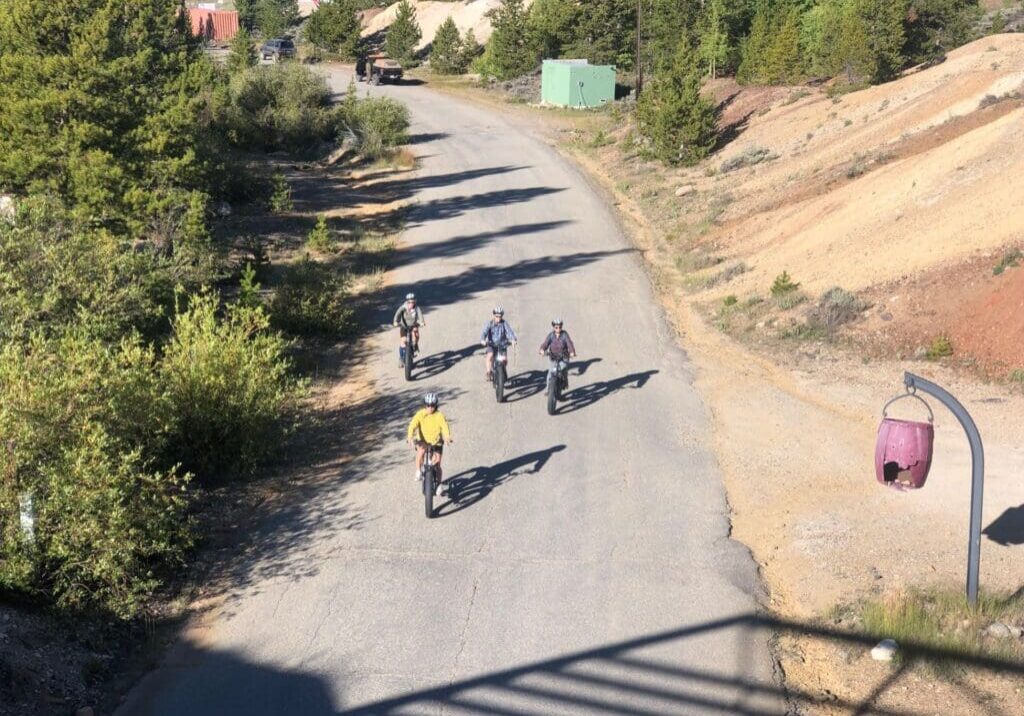 Four cyclists riding on a rural road.