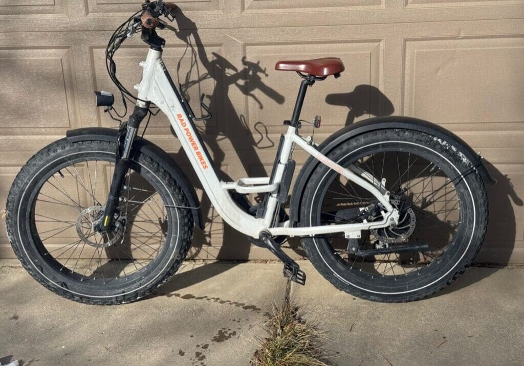 Electric bike parked against a garage wall.