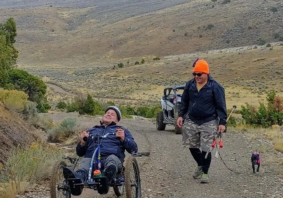 A man in a wheelchair is walking down the road