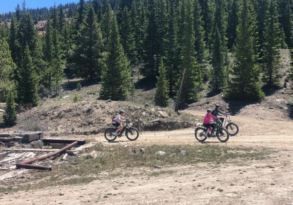 Two people riding bikes on a dirt road.