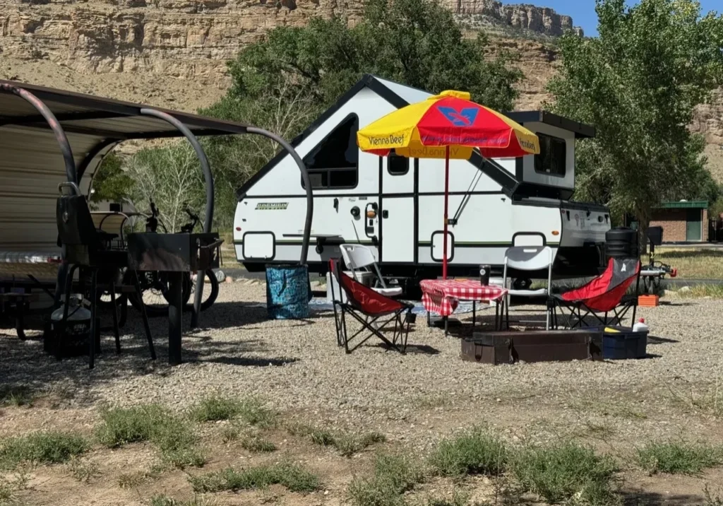 A white camper with an umbrella and some chairs