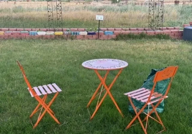 A table and two chairs in the grass.