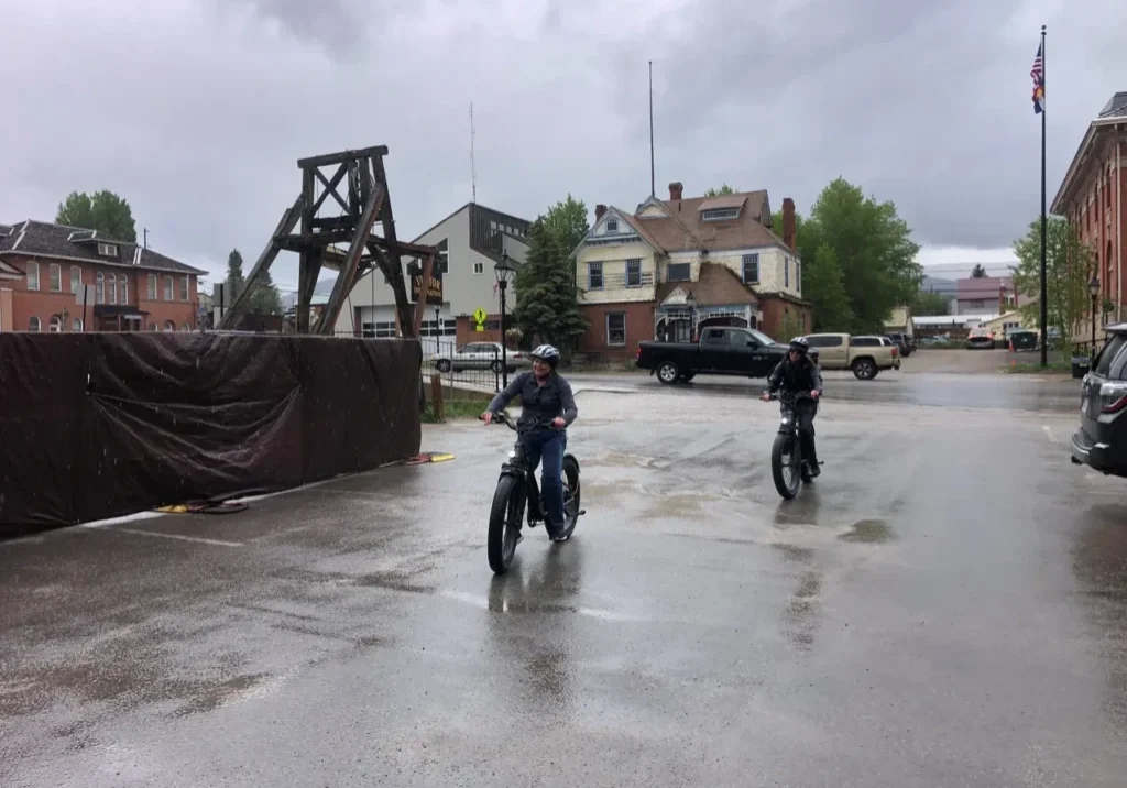 Two people riding motorcycles in a flooded area.